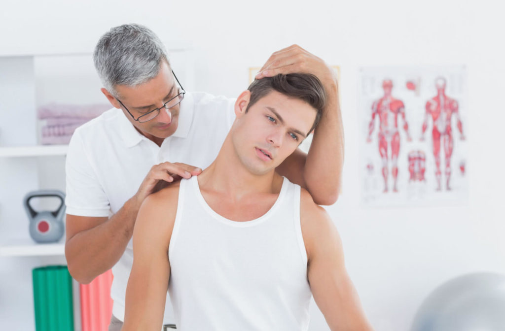 A male chiropractor is doing neck adjustments  to his male patient  in a  medical office