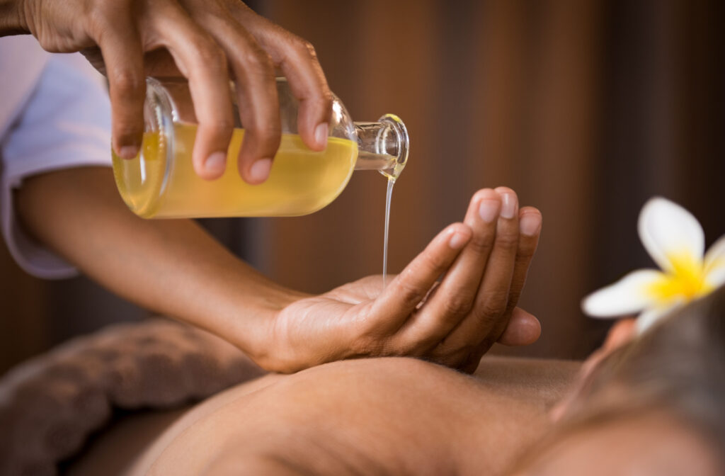 The masseuse pours essential oils into her palm, preparing to give an aromatic massage.