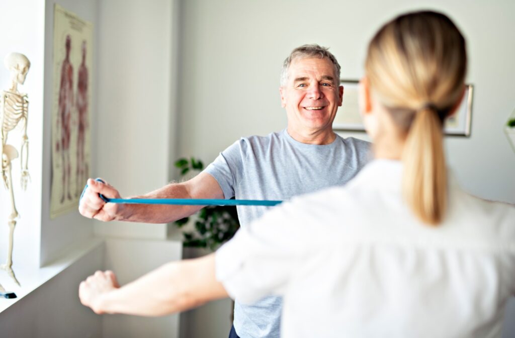 Person smiling while performing a resistance band exercise during a physiotherapy session.