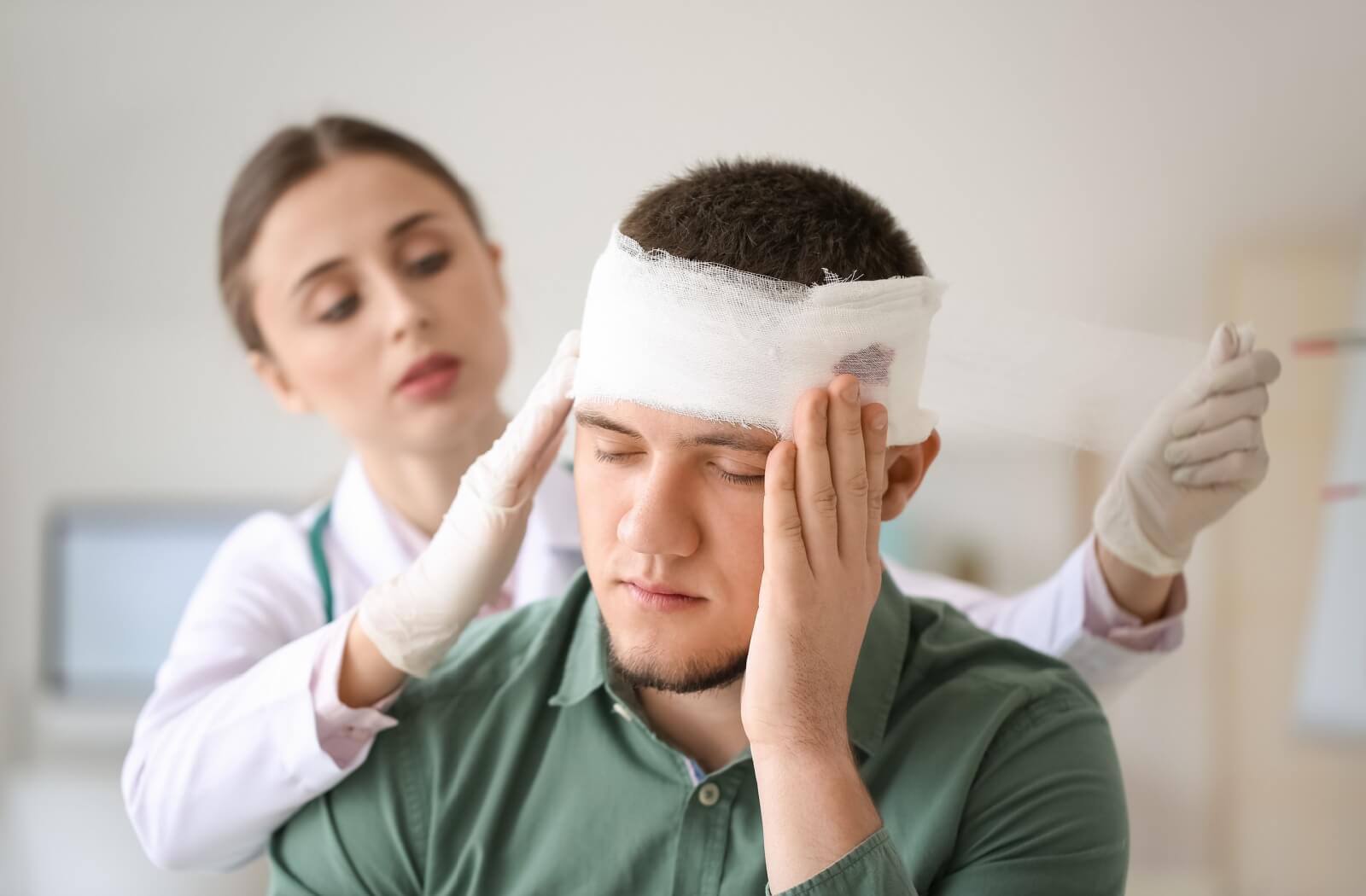 Healthcare provider wrapping head bandage for person with a concussion.